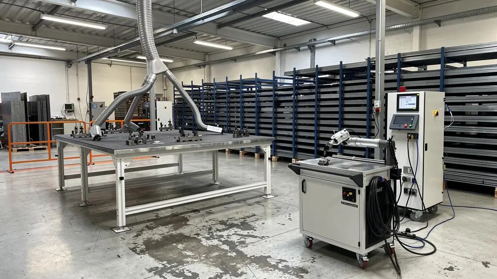 Vue d'ensemble d'un atelier de métallerie PME équipé d'un poste de soudage laser avec système d'extraction et zone de travail organisée
